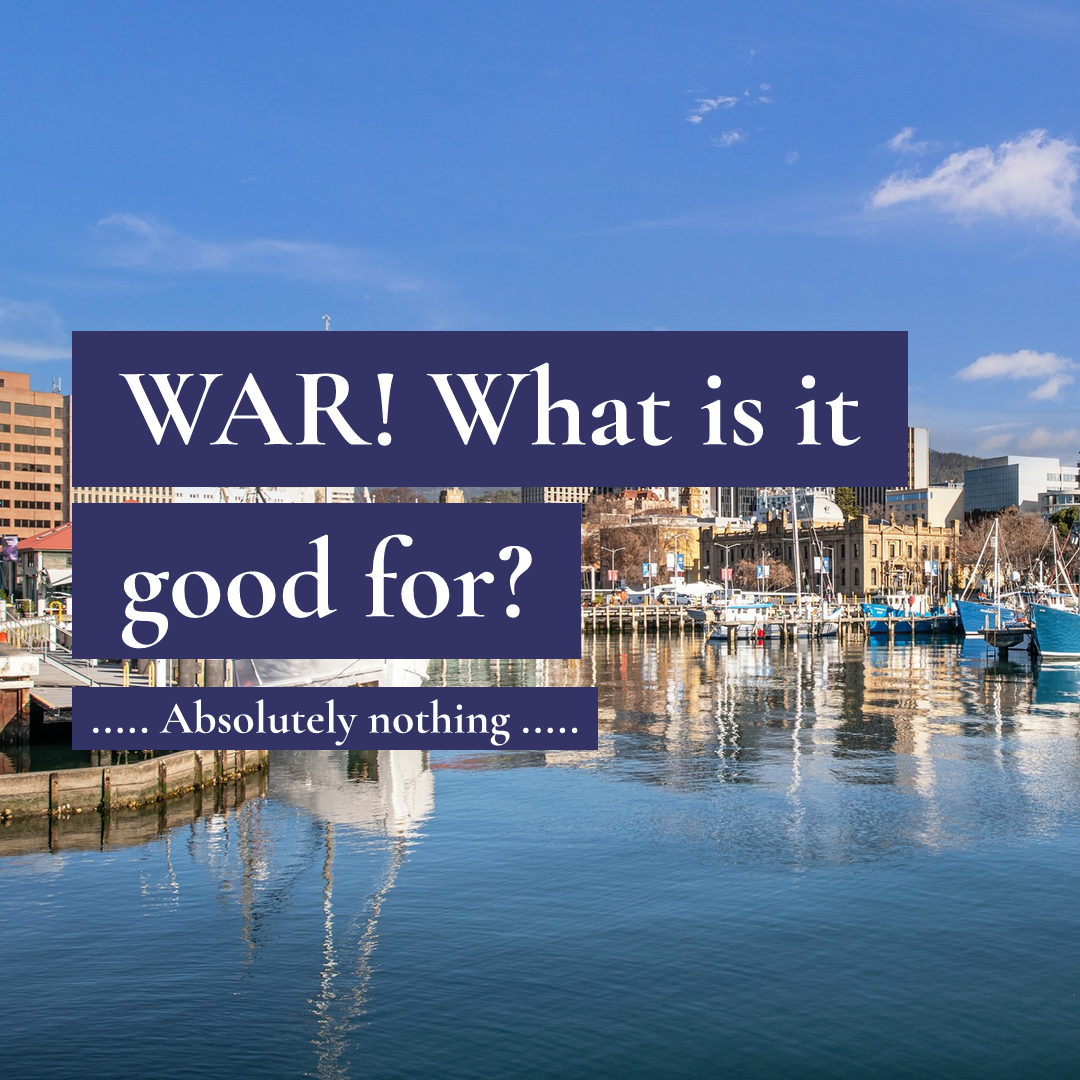 Boats in a harbour with city buildings, overlaid with text: WAR! What is it good for? Absolutely nothing.